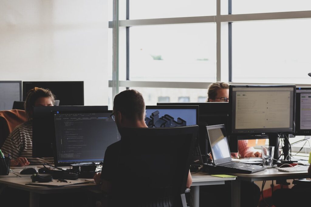 An office worker at a computer setting up a digital automation tool with documents and a phone nearby.