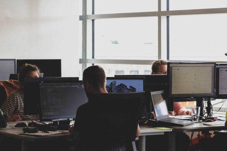 An office worker at a computer setting up a digital automation tool with documents and a phone nearby.