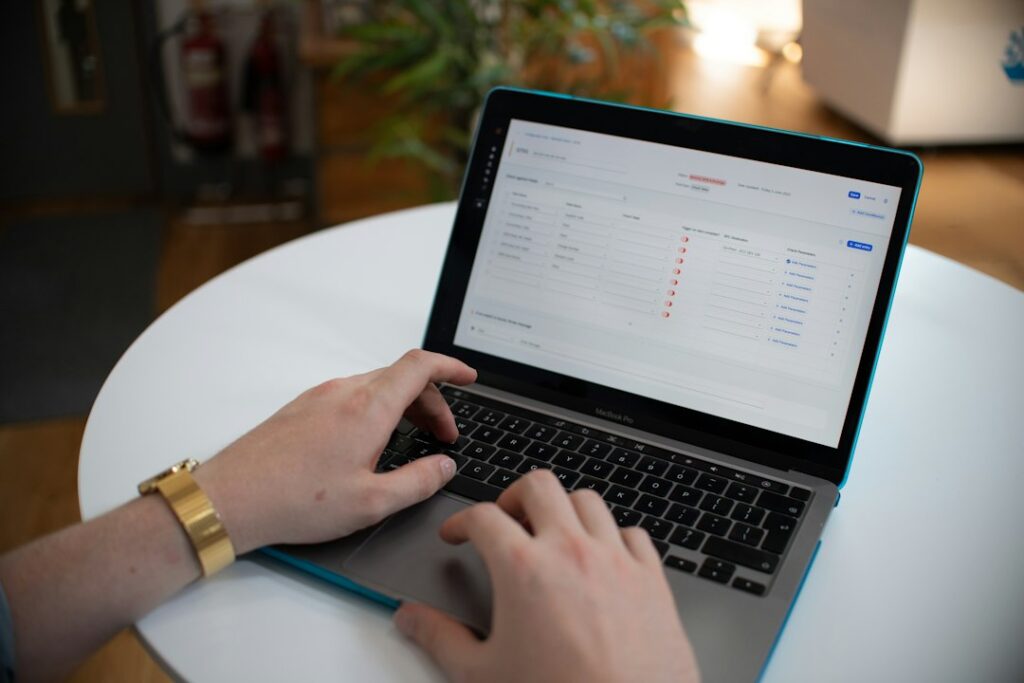 Employees review a workflow on a laptop beside organized documents and a digital task checklist.