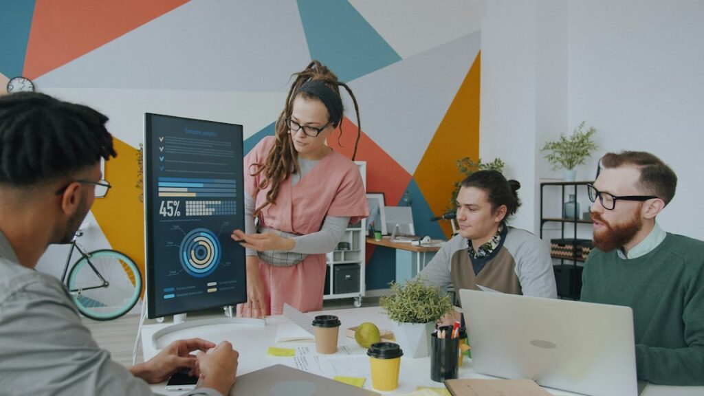 Employees review shared tasks and automated workflow updates on laptops around a workplace table.
